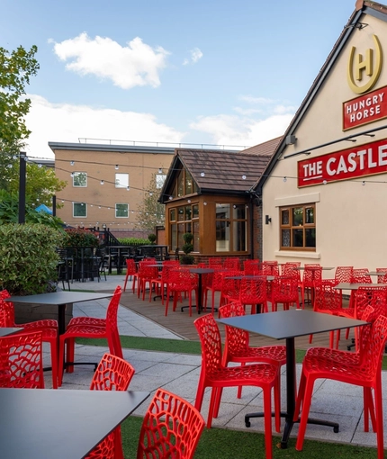 The exterior of the venue and beer garden seating area with tables, chairs, venue signage and string lighting at The Castle View.
