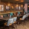 An interior restaurant seating area at the Rudds Arms; with a long, upholstered booth seat against one wall, with framed artwork above it.