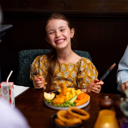 An image of a family enjoying various dishes and drinks within the interior restaurant seating area at a Community Pubs With Food venue.