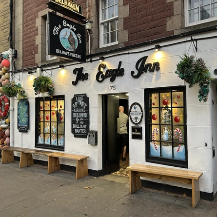 The exterior facade with outdoor seating benches at The Eagle Inn.