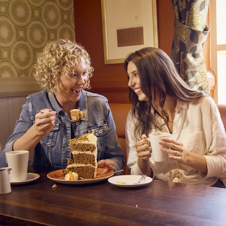Two people enjoying coffee & cake at a Farmhouse Inn venue.