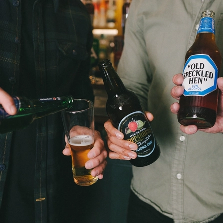 A group of friends holding low and no drinks in a cheers at a Greene King venue.