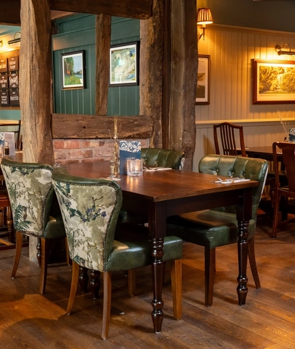 The interior restaurant seating area at The Rising Sun in Wistaston, with wood panelled walls, and wooden beams on the walls and ceiling.
