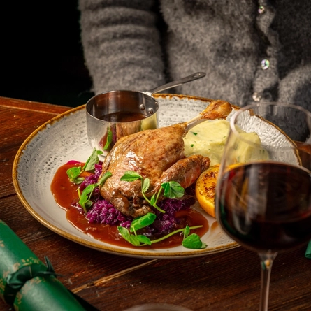 A plated meal on a festive decorated table.  A person whose face is not in teh image is seated at the table.