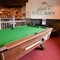 Interior seating area of a pub with a pool table and a bar.