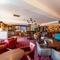 Interior dining area of a pub with a bar, a dartboard, a TV and a pool table.