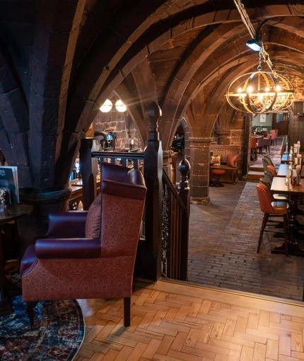 The interior bar and multi level restaurant seating area with tables, chairs, gothic stone vaulted ceiling and tiled flooring at The Watergates Bar.