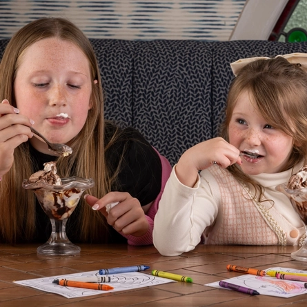 Two children enjoying an ice-cream sundae served at a Flaming Grill venue.