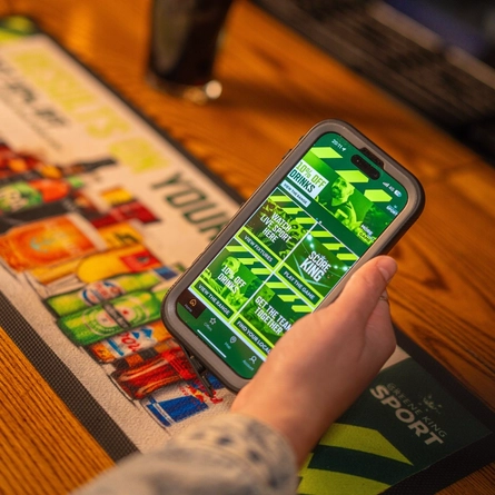 a woman buying a beer at a Greene King pub using the 10% discount available on the app