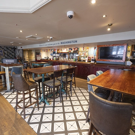 Interior dining area of a pub with a bar and a few TVs.