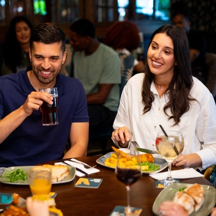 An image of a family enjoying various dishes and drinks within the interior restaurant seating area at a Community Pubs With Food venue.
