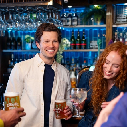 A group of people by the bar enjoying drinks.