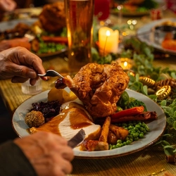 An image of a customer cutting into a plated Turkey dinner dish available over Christmas at Venture Hotels.