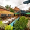 The exterior beer garden seating area at The Talbot in Worcester; with wood picnic tables, shade umbrellas, planter boxes, string lights overhead, and a large wooden pergola with under cover seating.