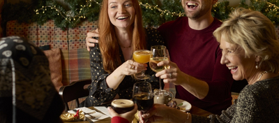 A banner showing a group of people sat at a table enjoying Festive Drinks within the interior seating area at a Chef & Brewer venue.
