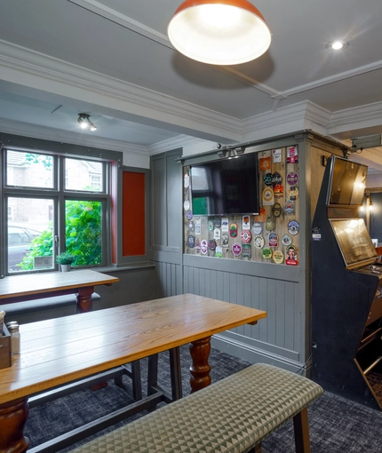 Interior dining area of a pub with a gambling machine and a TV.
