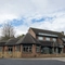 The exterior facade, signage, and seating area at the Devonshire Arms in Sheffield, with an accessibility ramp, wooden picnic tables, shade umbrellas, and string lights.