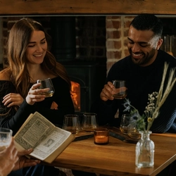 An image of 3 customers enjoying a Burns Night Whiskey flight board sat at a table within the interior restaurant seating area of The Crown.