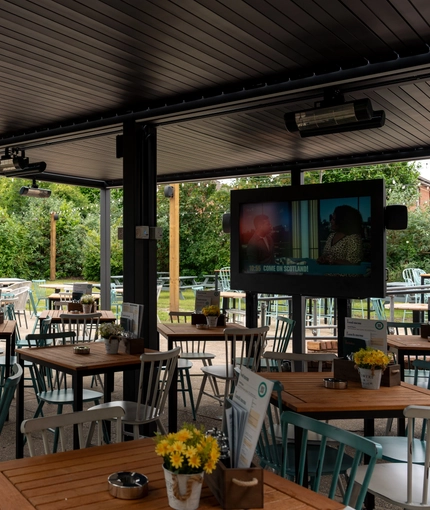 The under cover exterior beer garden seating area at The Richmond Arms, with heaters and an outdoor TV.