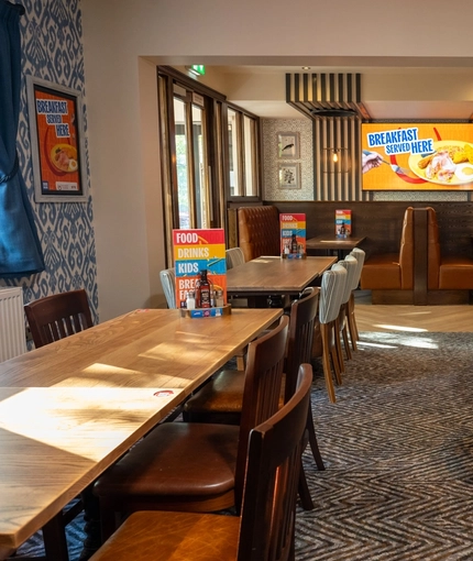 The interior restaurant seating area with tables, chairs, seating booths and wall mounted TV at The Castle View.