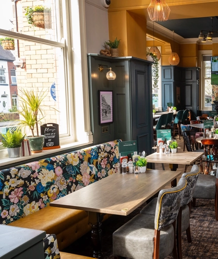 An interior restaurant seating area at The Victoria, with upholstered chairs, a fireplace, and a TV on the wall.