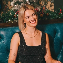 A person sitting at a restaurant table, holding a knife and fork. Plates of food, Christmas crackers, and a glass of Level Head IPA sit on the table in front of them.