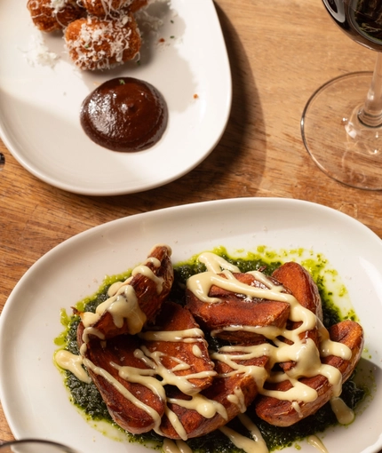 An advertising image of a selection of snack dishes and various drinks sat on a table within the interior restaurant and seating area at The Ubiquitous Chip.