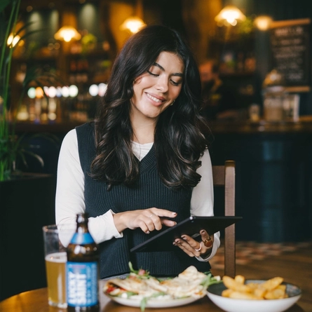 A lifestyle image of a person sat within the interior restaurant seating area enjoying a lunch dish and a drink available at Urban Core venues.
