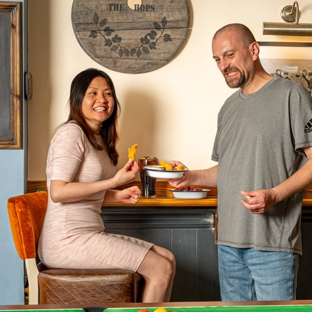 An image of 2 children playing pool and 2 adults enjoying food and drinks within the interior of a Hungry Horse venue.