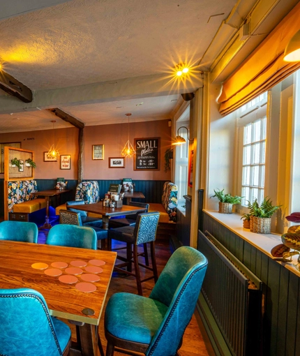An interior restaurant seating area at The White Hart, with upholstered seats, and potted plants on the window sill.