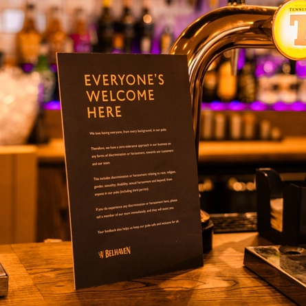 An Everyone's Welcome Here sign on a bar.