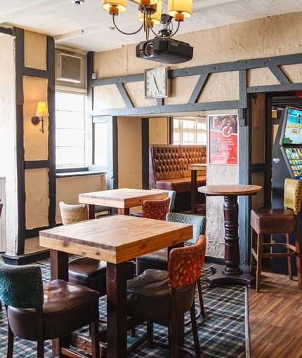 Interior seating area of a pub with a TV, a fireplace, a pool table and a gambling machine.