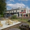 The exterior facade, signage, and beer garden seating area at The Cherry Tree in Newcastle-Under-Lyme; with wooden picnic tables, shade umbrellas, and string lights overhead.