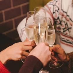 An image of a group of people holding glasses of Sparkling White Wine celebrating with a cheers within the interior seating area of a Greene King venue.