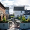 The exterior facade and beer garden seating area of The Fox in Bury St Edmunds, with plants in raised planter boxes and string lights above the tables and chairs.