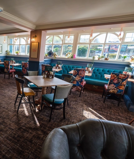 An interior restaurant seating area at The Talbot Inn, with booth window seats, upholstered chairs, and a fireplace.
