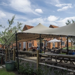 The exterior beer garden seating area with partial undercover section and the venue in the background at The Crown.