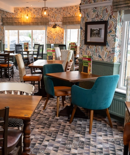 An interior restaurant seating area at the Devonshire Arms, with framed artwork on the walls.