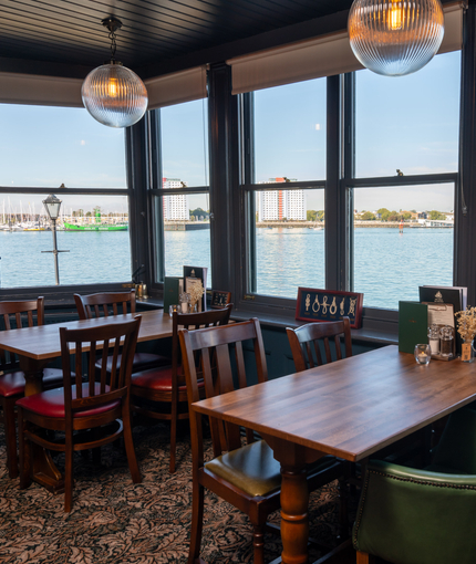 The interior restaurant seating area with tables, chairs and a seaview from the window at The Spice Island.