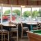 The interior games area at The Tamar, with a dartboard, a pool table, and tables and chairs next to the windows.