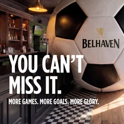 A banner promoting the new football season at Belhaven venues. The banner shows an interior of a Belhaven-branded sports bar featuring a giant football-shaped wall installation beside the bar. Large white text reads “YOU CAN’T MISS IT.” with smaller text underneath stating “MORE GAMES. MORE GOALS. MORE GLORY.” A television screen showing a football match is visible in the background above beer taps and shelves of bottles.