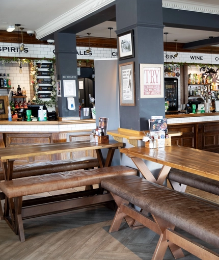 Interior dining area of a pub with a bar and a gambling machine.
