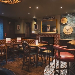 The interior restaurant seating area at the Albanach in Edinburgh with an upholstered booth corner seat and a fireplace.