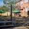 The exterior beer garden seating area at the Green Posts, with wooden picnic tables, shade umbrellas, a TV, and string lights overhead.