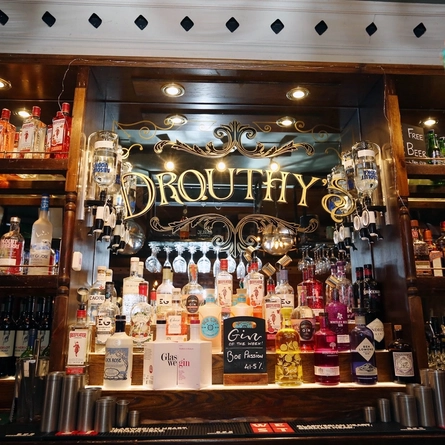 Various bottles and venue signage on a mirror behind the interior bar at Drouthys.