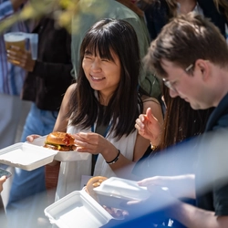 An image of a group of people stood outside with food talking during the Boat race event at The Crabtree.