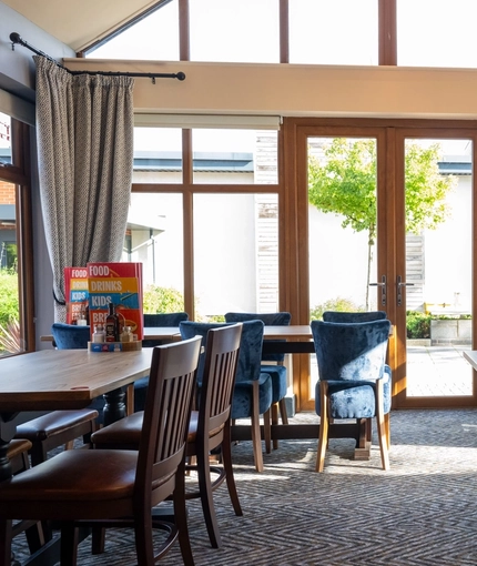 The interior conservatory style restaurant seating area with tables, chairs, vaulted ceiling and large patio style doors at The Castle View.