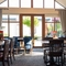The interior conservatory style restaurant seating area with tables, chairs, vaulted ceiling and large patio style doors at The Castle View.