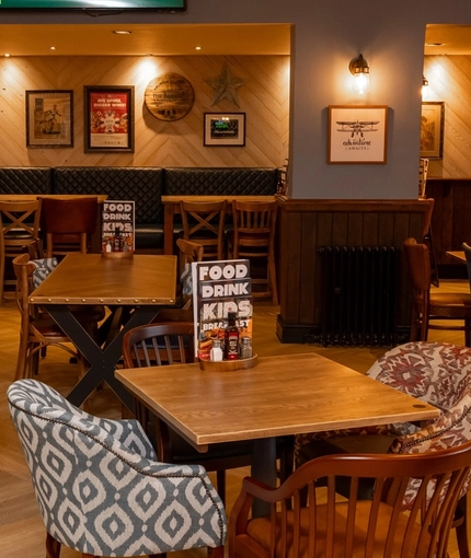 The interior restaurant seating area at The Railway, with TVs on the walls, and upholstered booth seats.