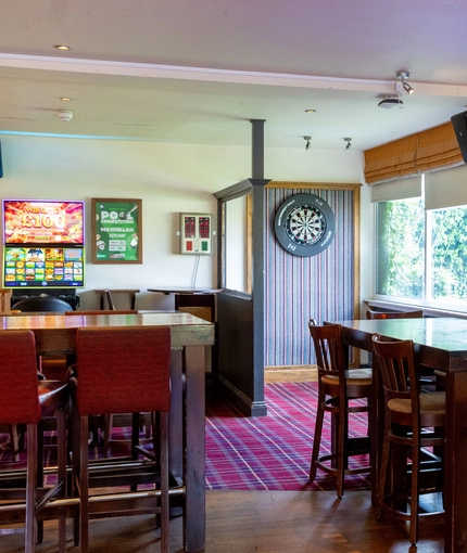 Interior dining area of a pub with a TV, a gambling machine and a dartboard.